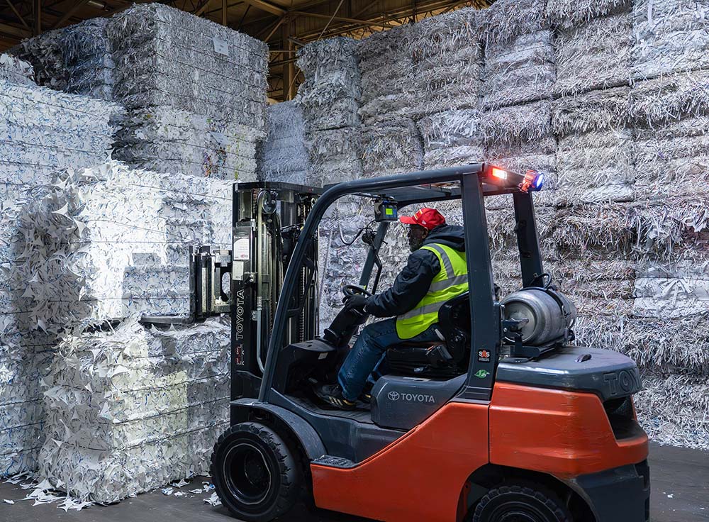 Man driving a forklift preparing to lift a pallet of shredded paper